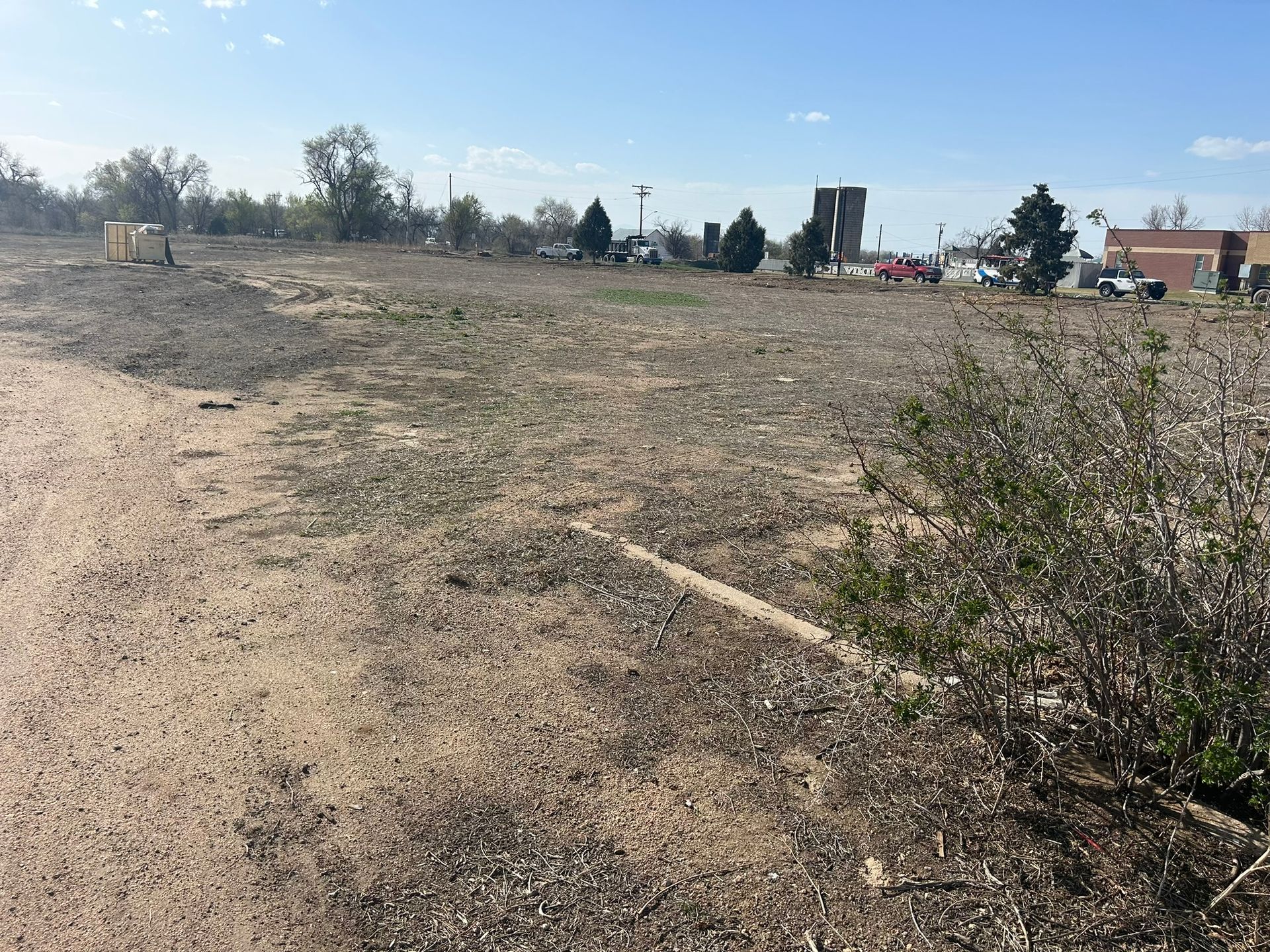 A dirt road going through a field with a building in the background