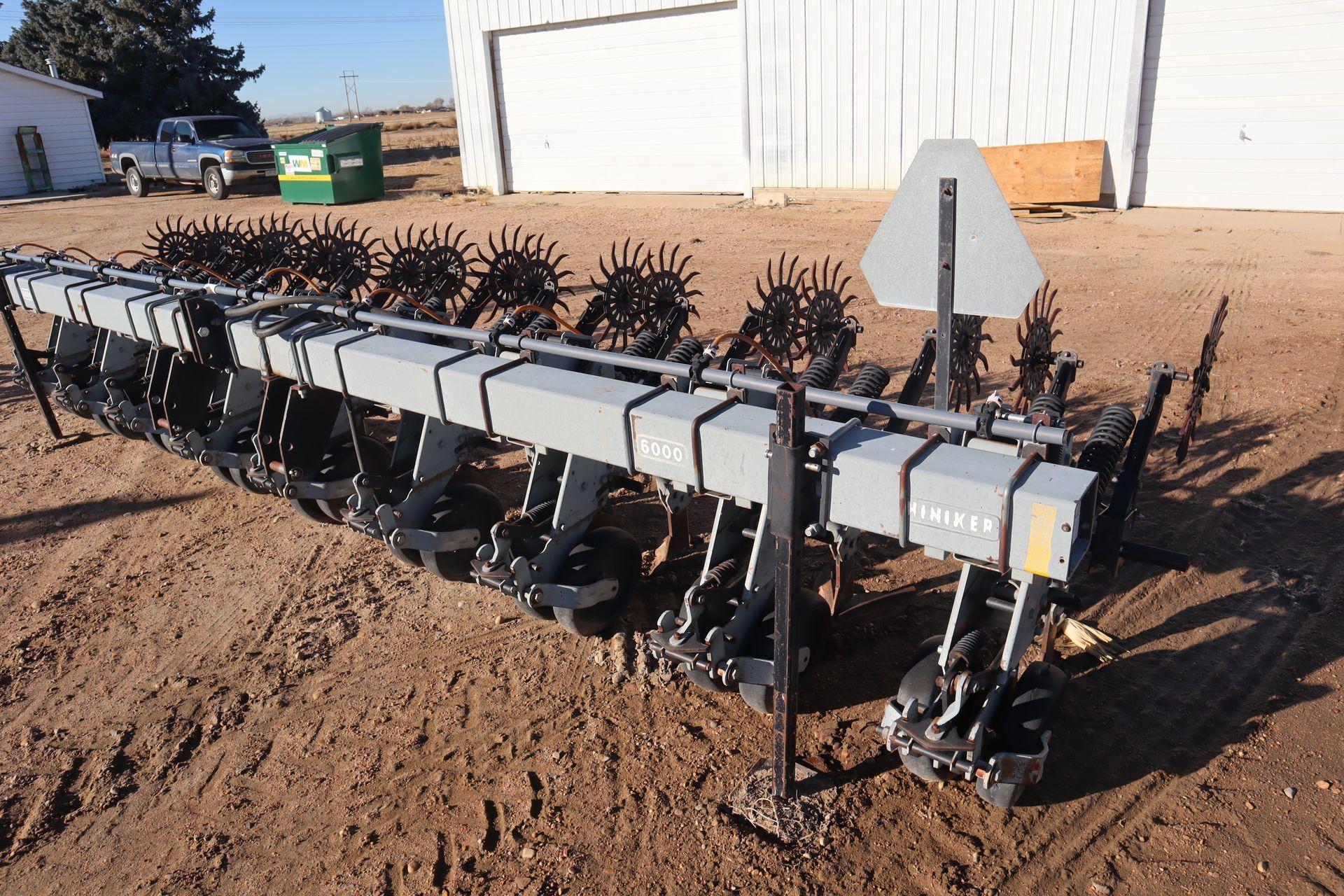 A large machine is sitting in the dirt in front of a building