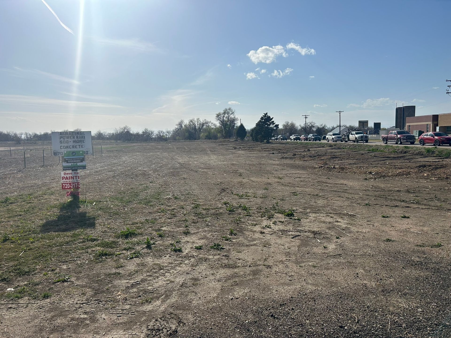 A large dirt field with a for sale sign in the middle
