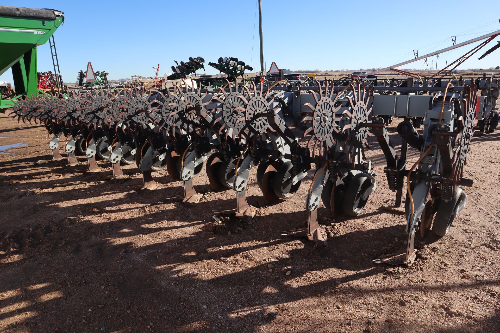 A row of tractors are parked in a dirt field