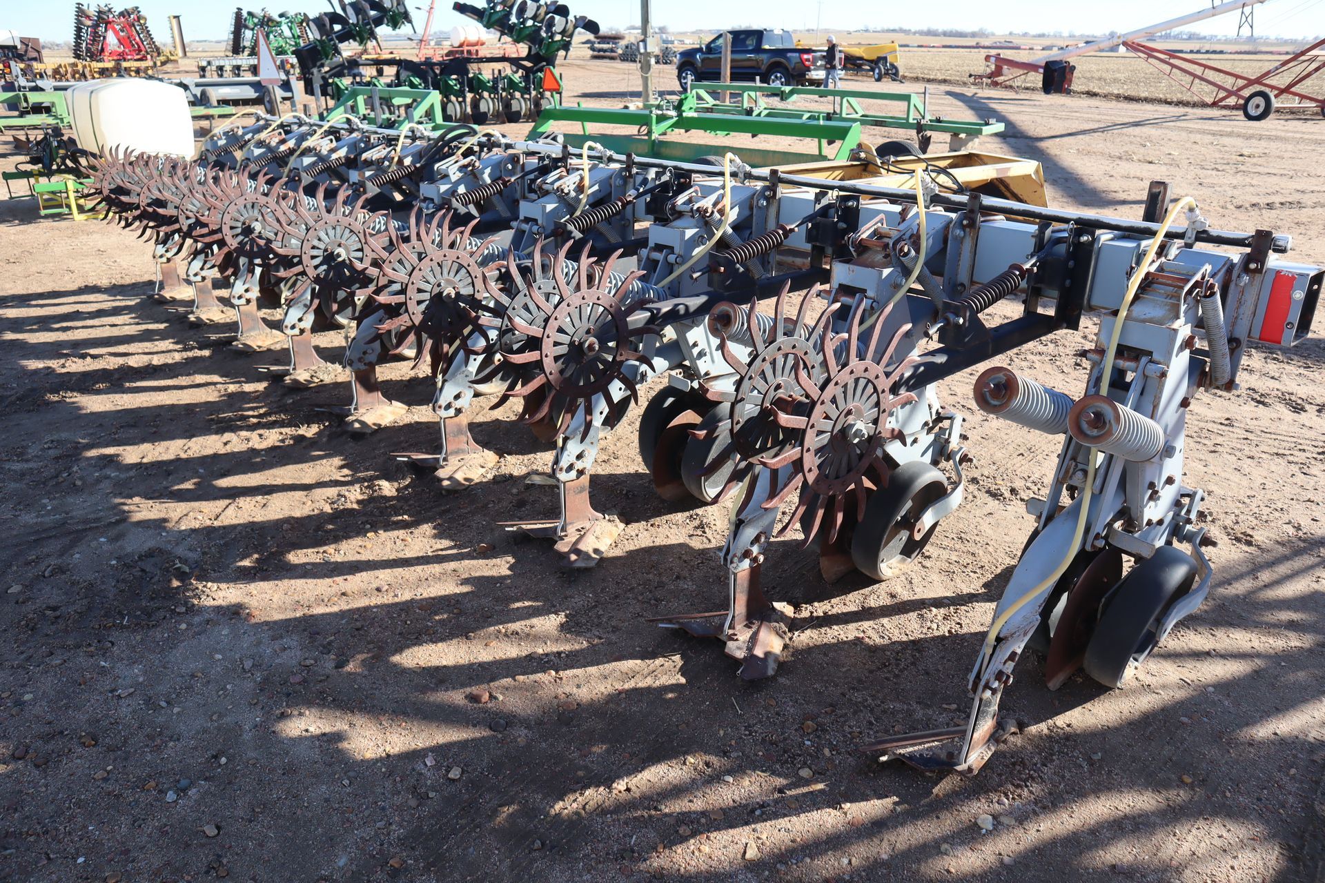 A row of tractors are parked in a dirt field