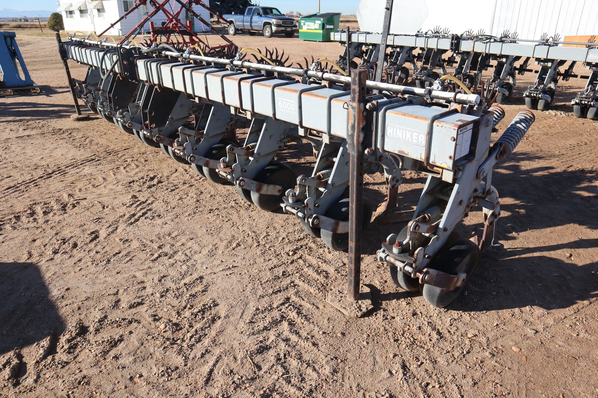 A row of tractors are parked in a dirt field