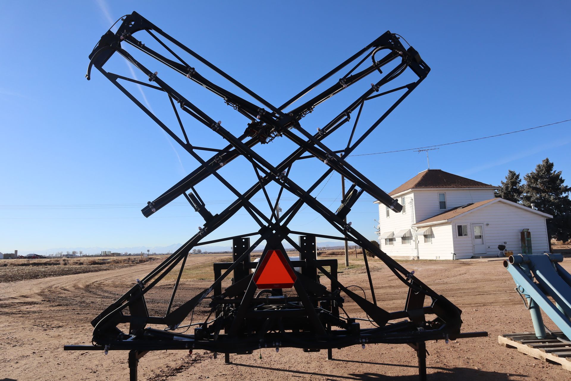 A large black object with a red triangle on it is in front of a white house