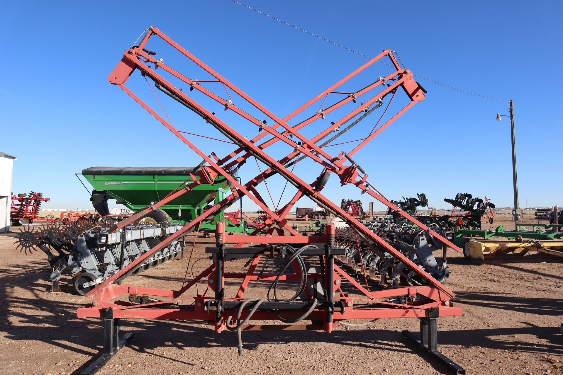 A red and green machine is sitting in a dirt field.
