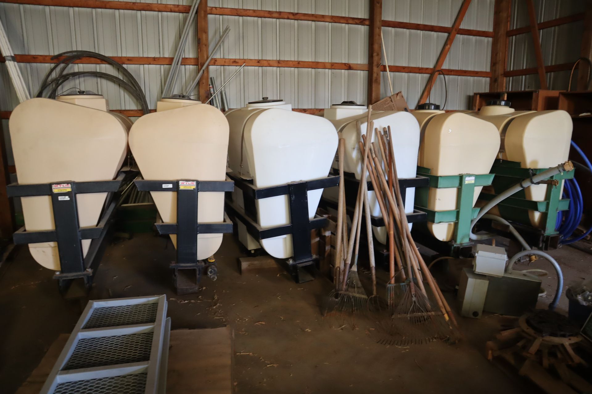 A row of white tanks are lined up in a barn.