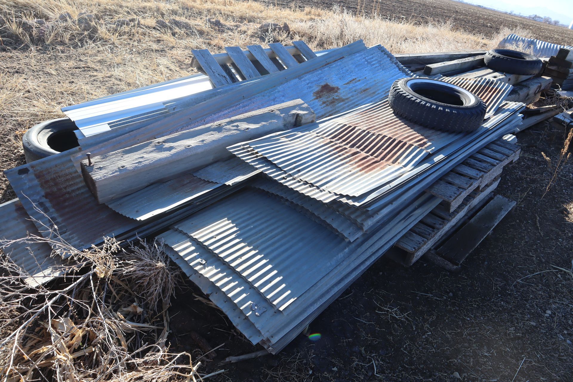 A pile of metal is laying on the ground in a field.