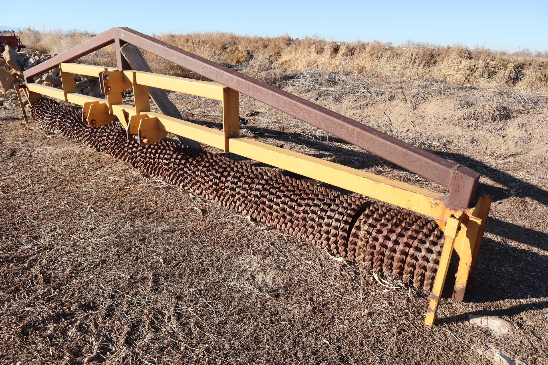 A wooden fence is sitting in the middle of a dirt field.