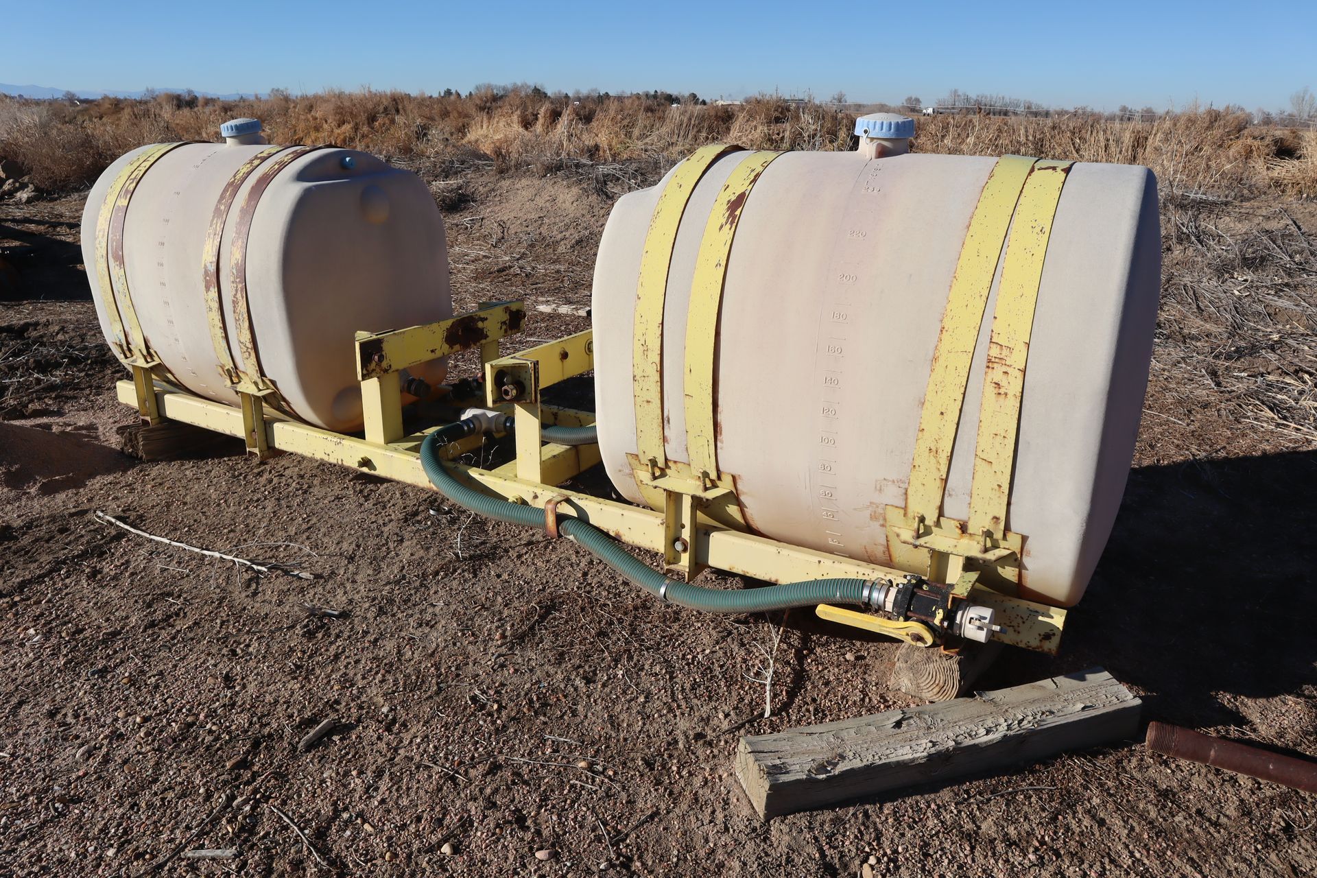 A couple of barrels are sitting on top of a dirt field.