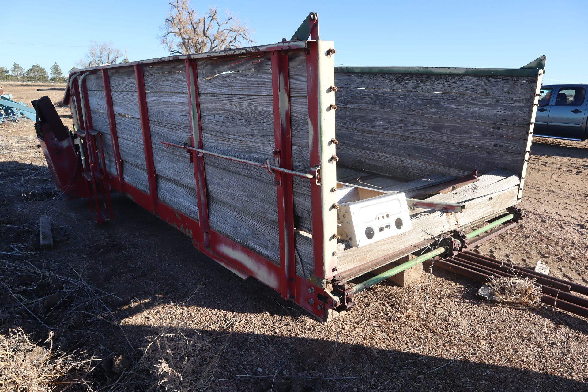 A red and white wooden trailer is sitting in the dirt.