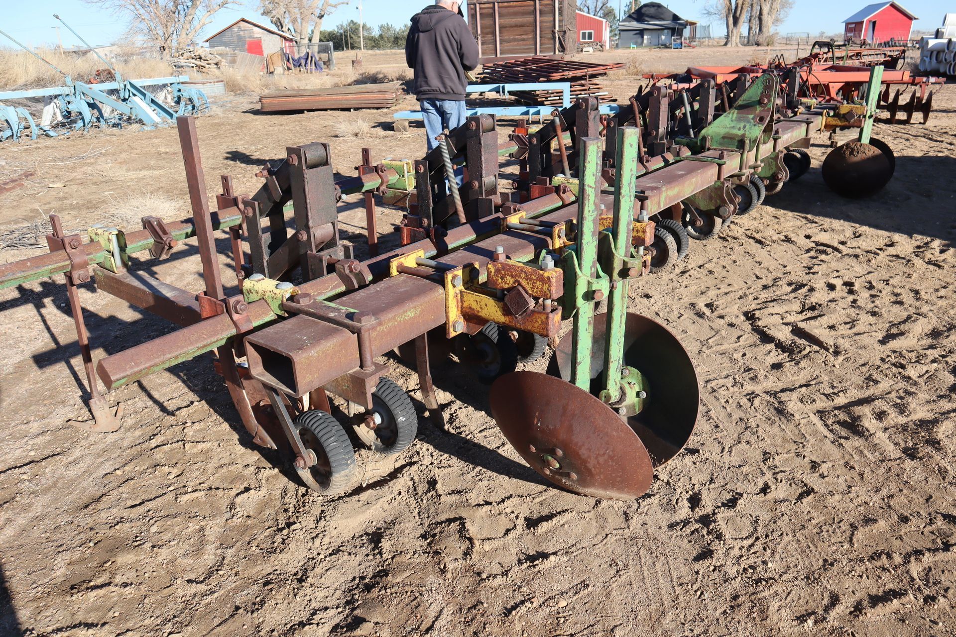 A man is standing next to a plow in the dirt.