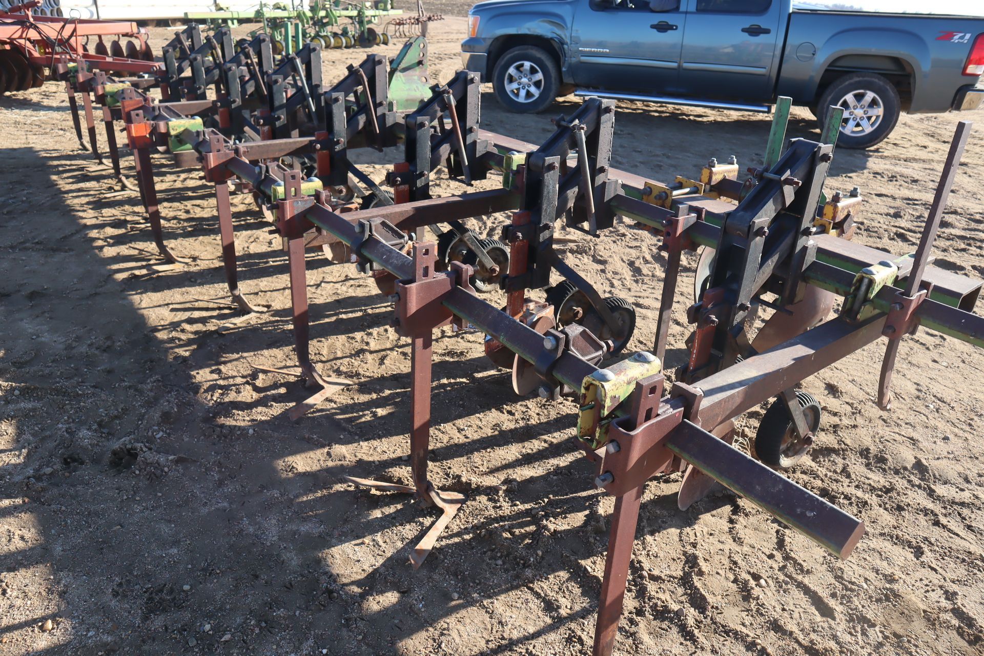 A truck is parked in the dirt next to a row of metal pieces.