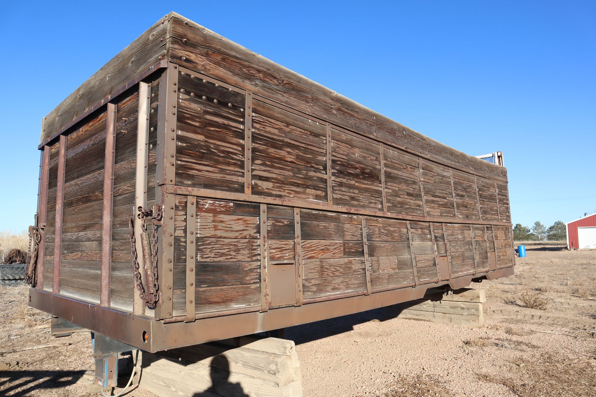 A large wooden box is sitting in the middle of a dirt field