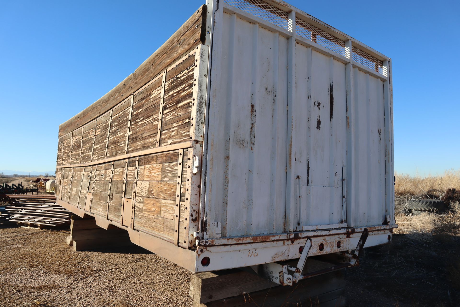 A large white container is sitting in a dirt field.