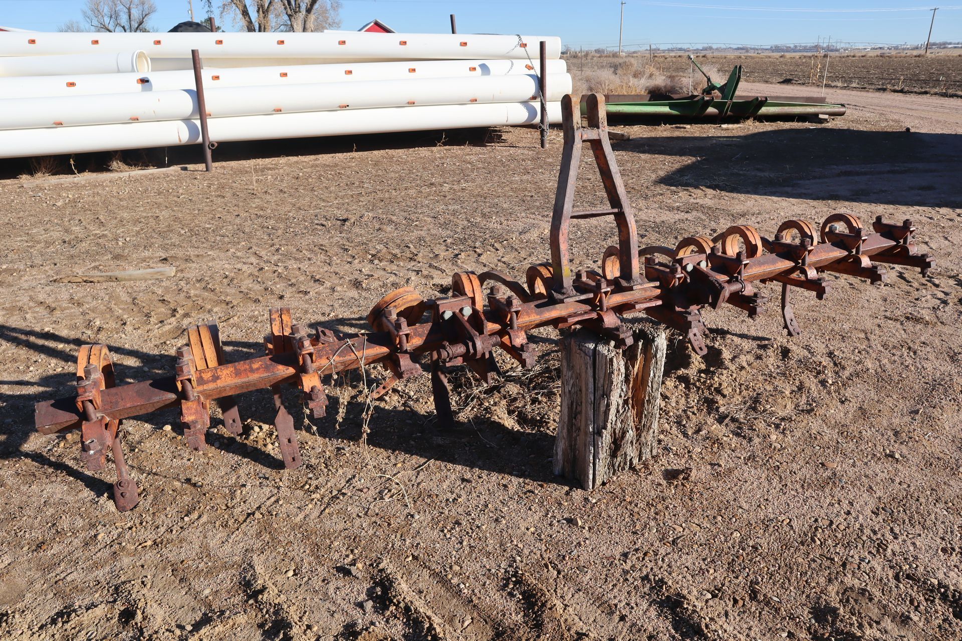 A rusty piece of equipment is sitting in the middle of a dirt field.