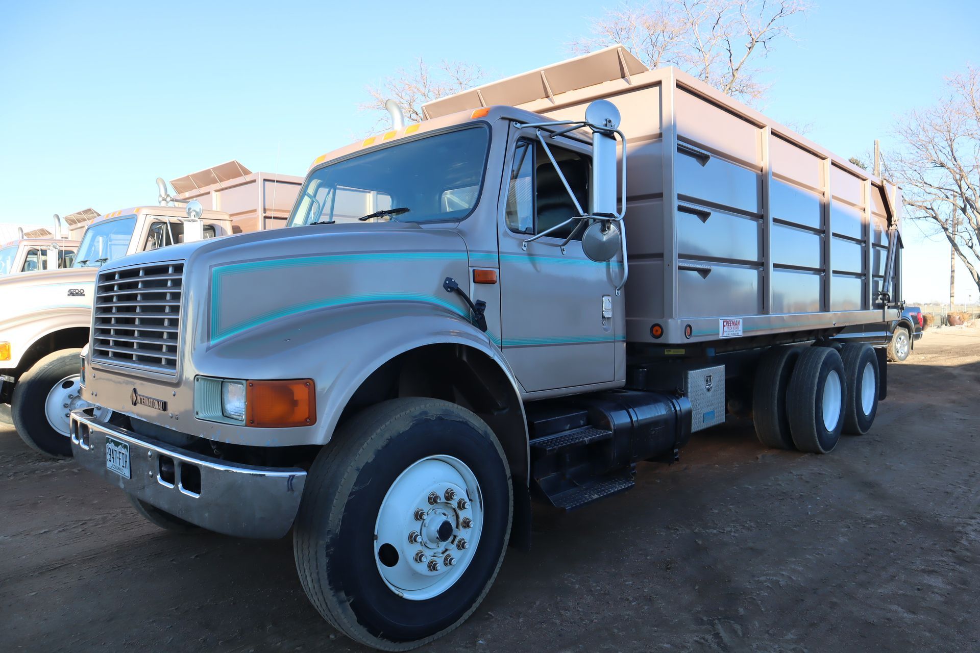 A dump truck is parked in a dirt field.