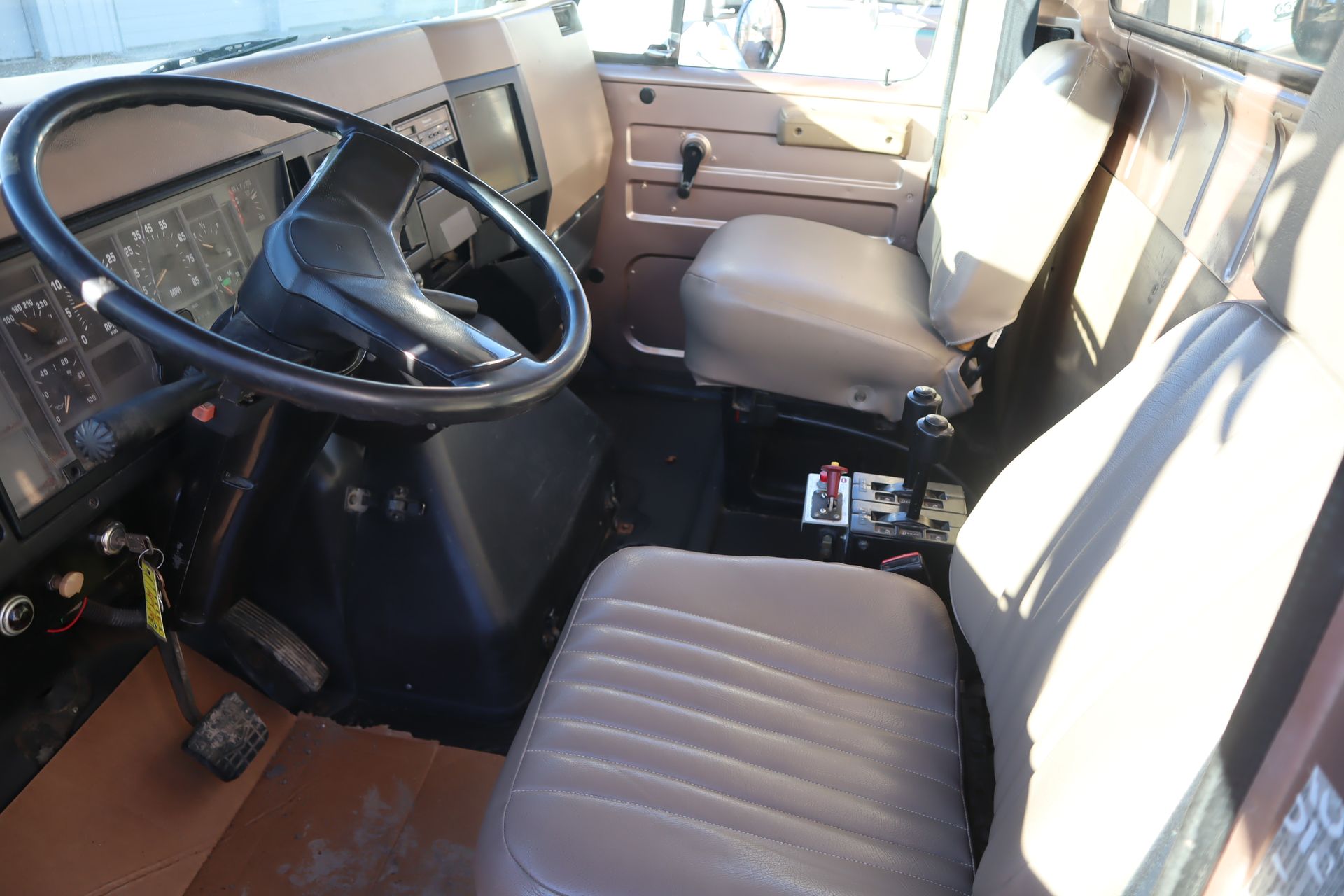 The inside of a truck with a steering wheel and seats
