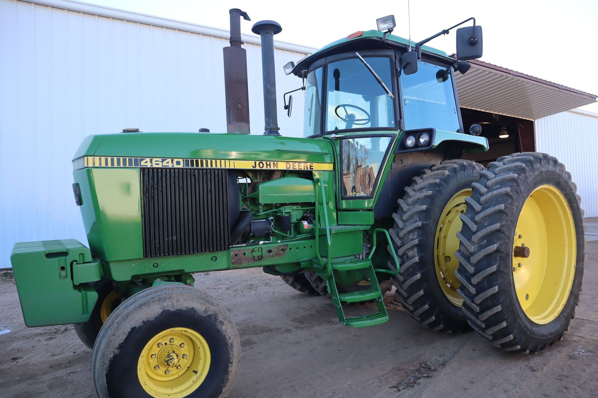 A green john deere tractor is parked in front of a building