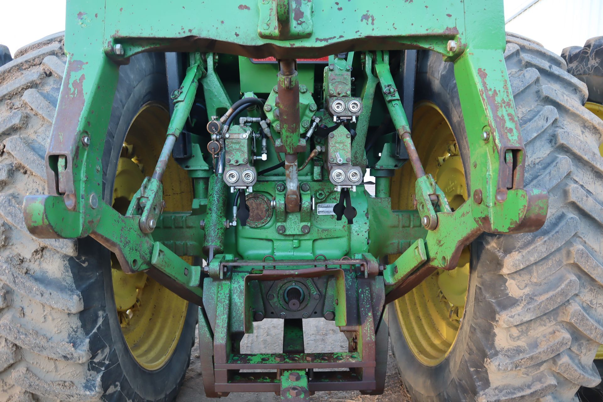 A green john deere tractor is parked in the dirt