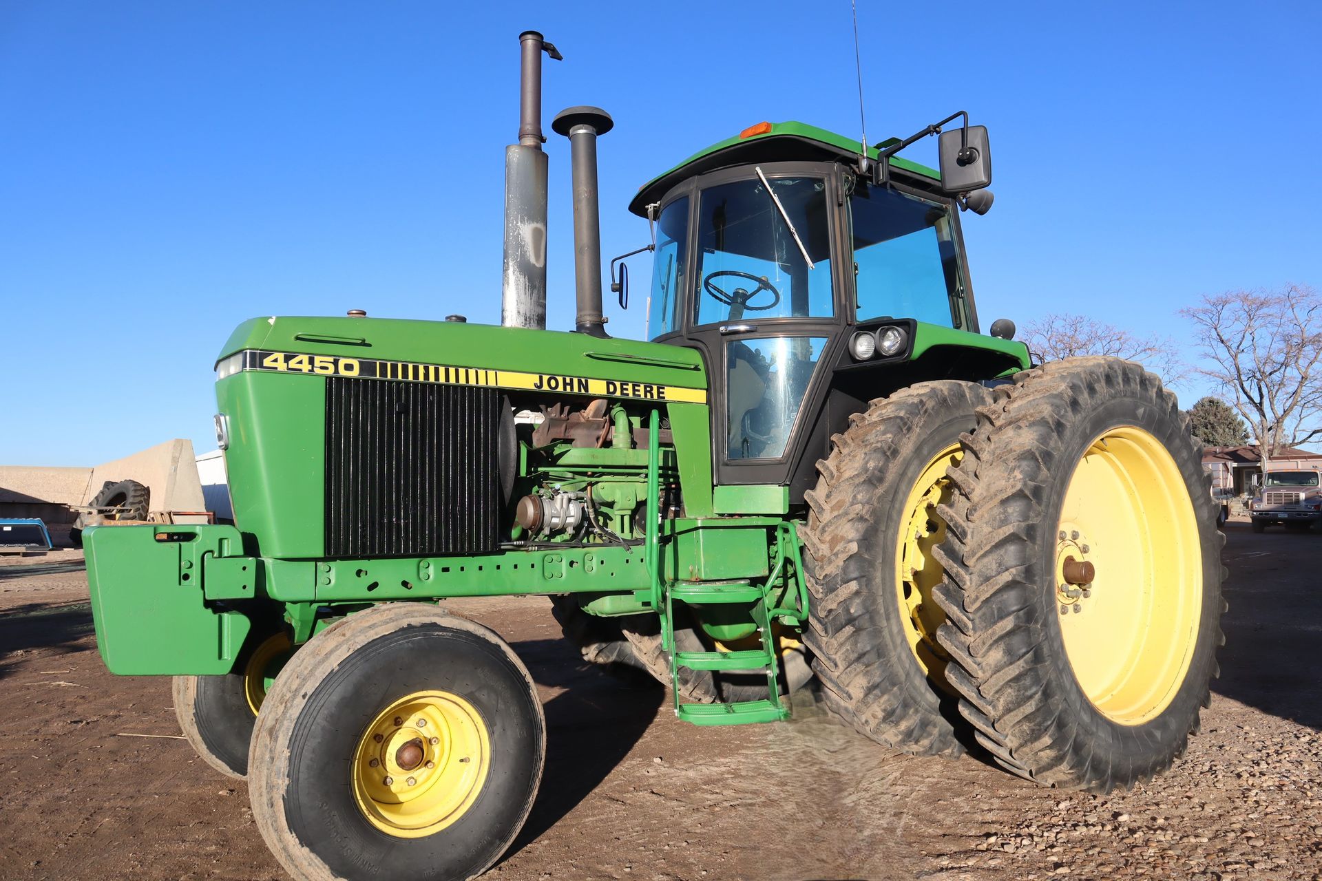 A green john deere tractor is parked in a dirt field