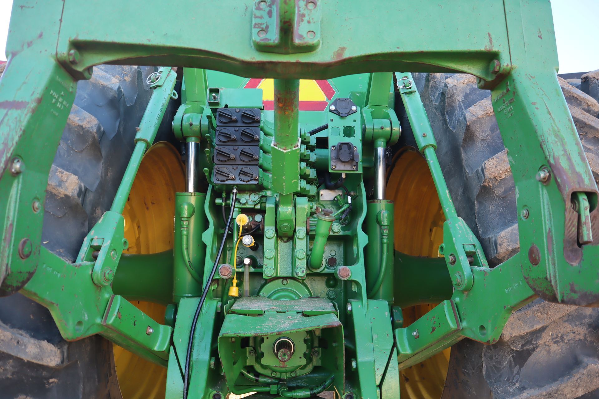 A green and yellow tractor with a yellow warning sign on it