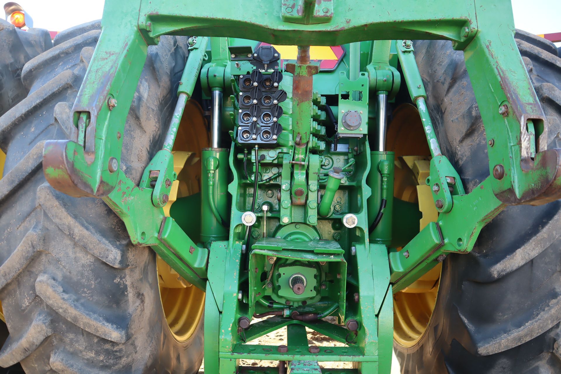 The back of a green and yellow tractor with large tires