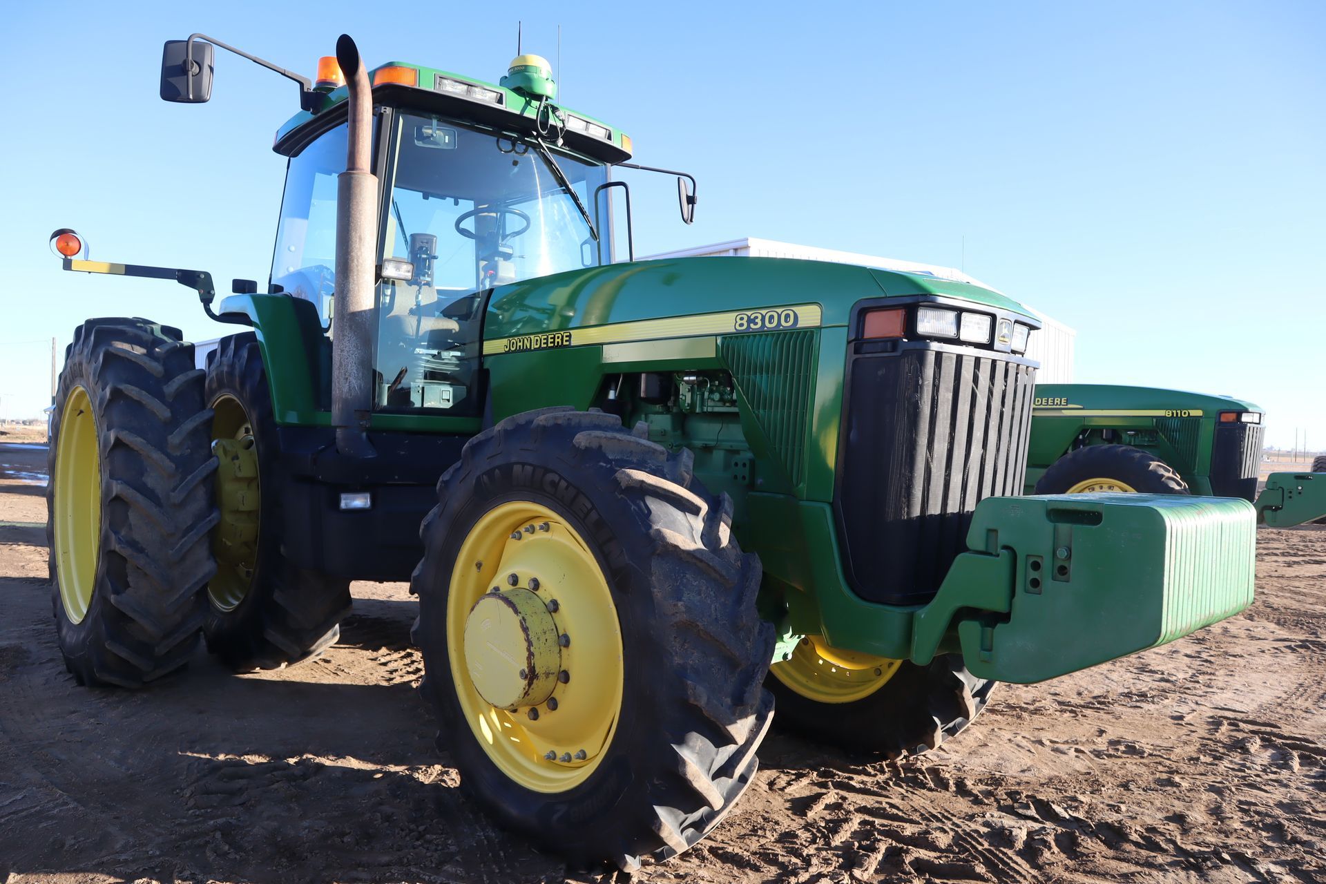 A john deere tractor is parked in a dirt field