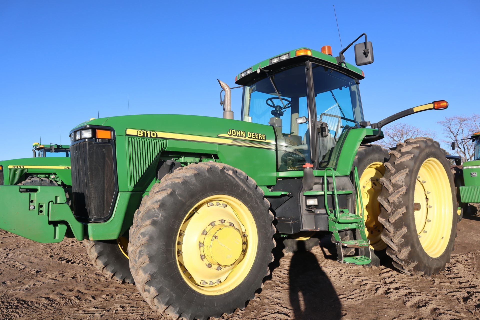 A green john deere tractor is parked in a dirt field