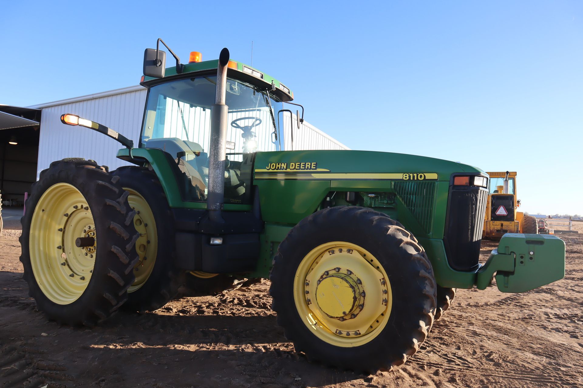 A john deere tractor is parked in a dirt field