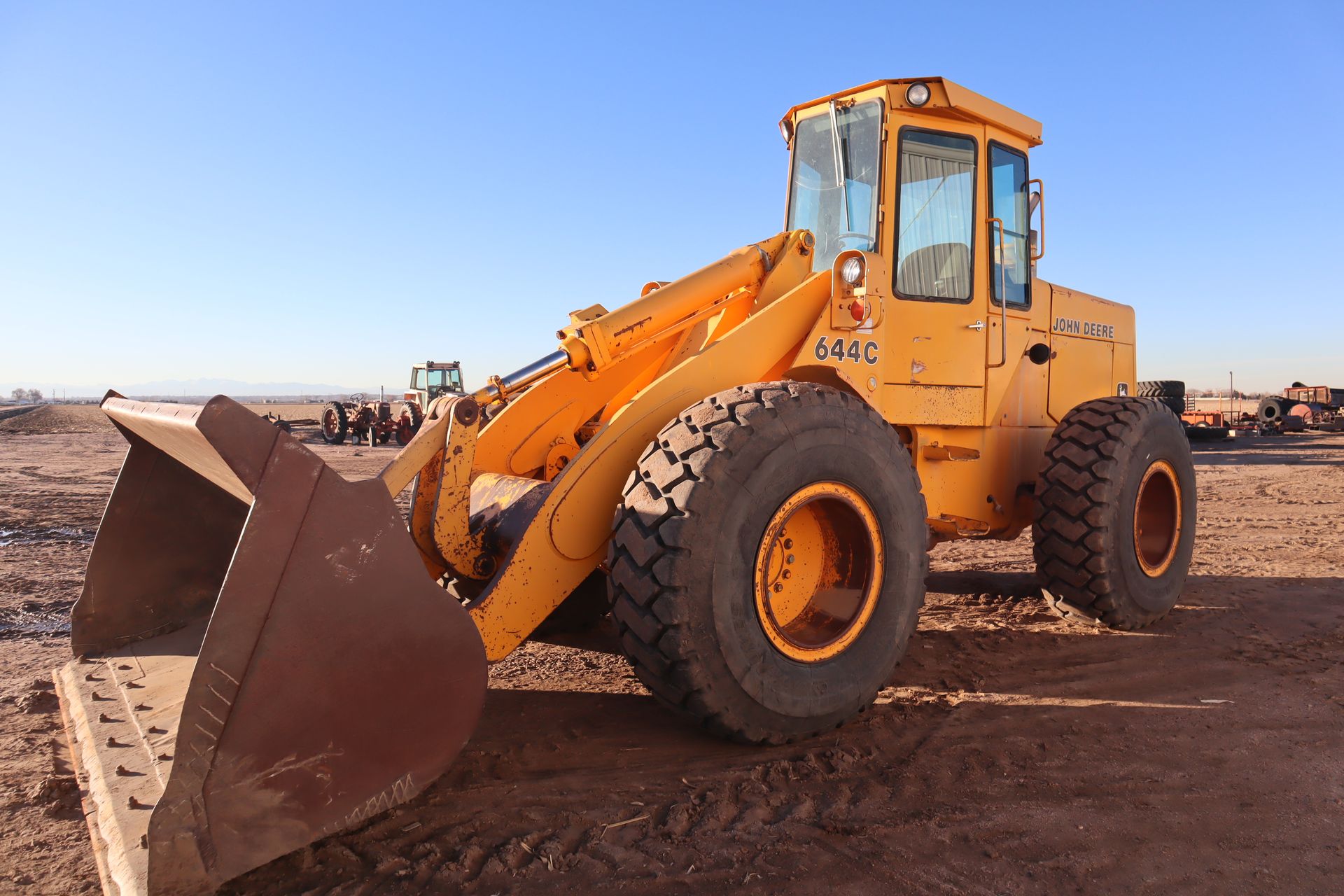 A yellow bulldozer is parked in a dirt field