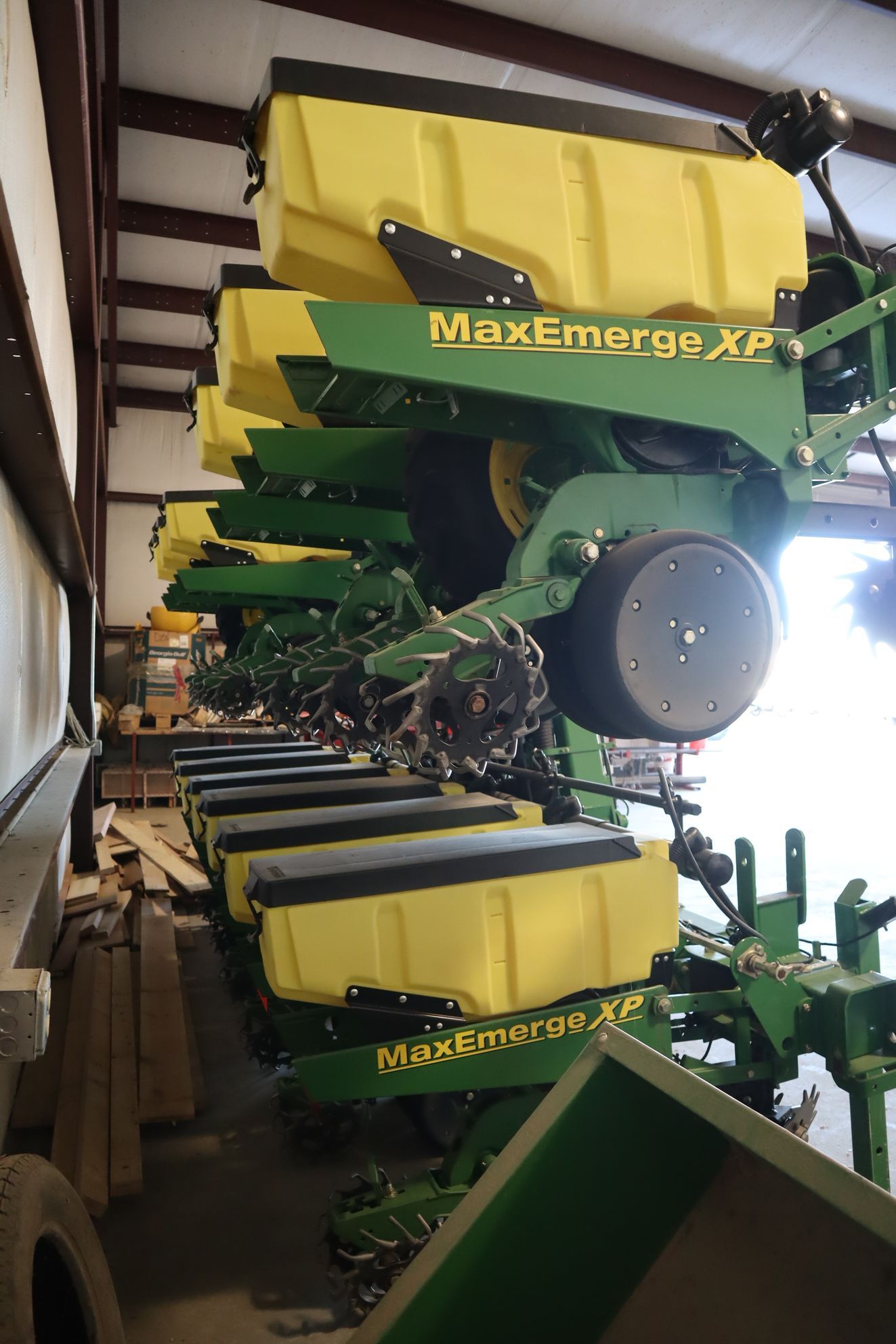A john deere planter is sitting in a warehouse.