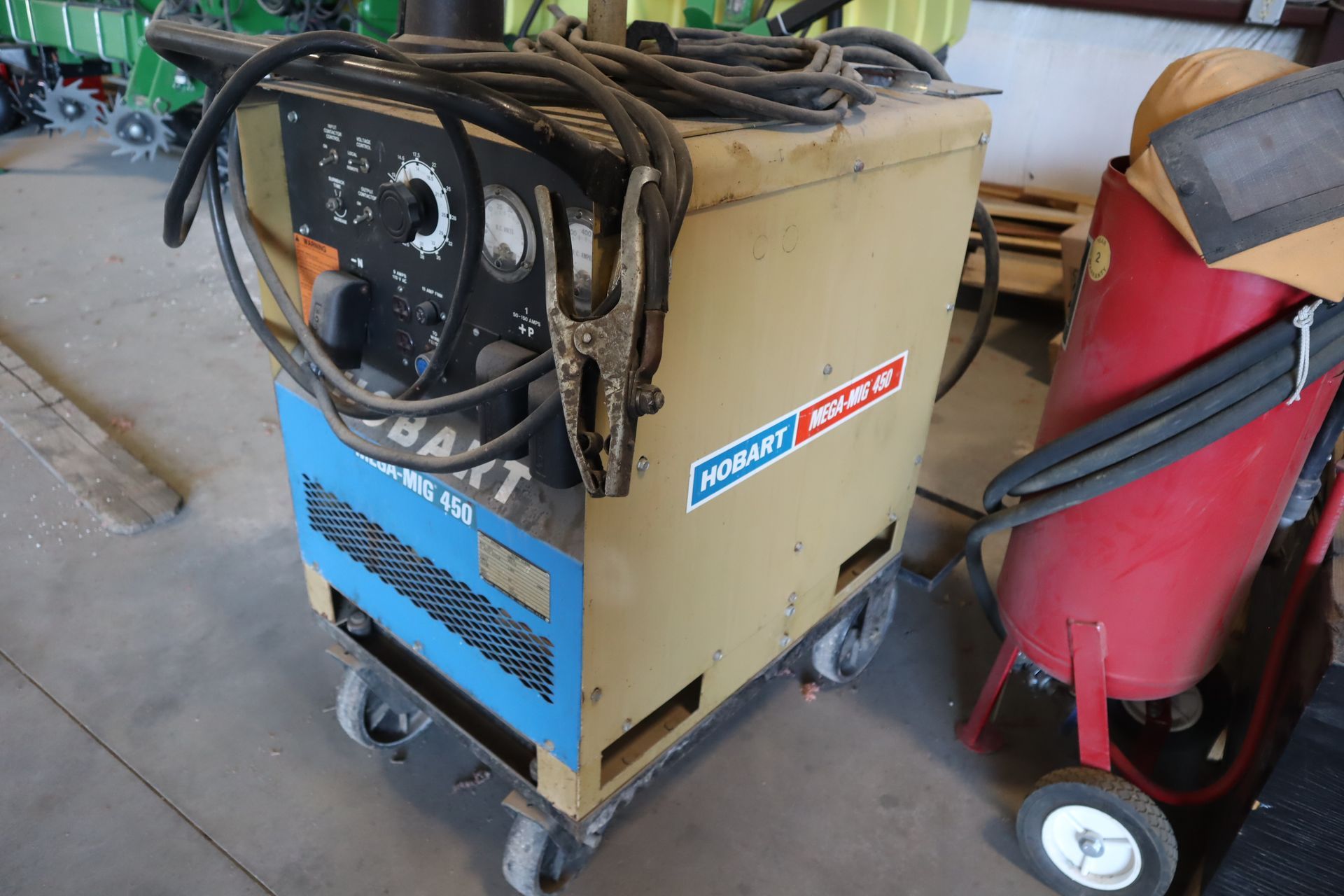 A welding machine is sitting on a cart in a garage.