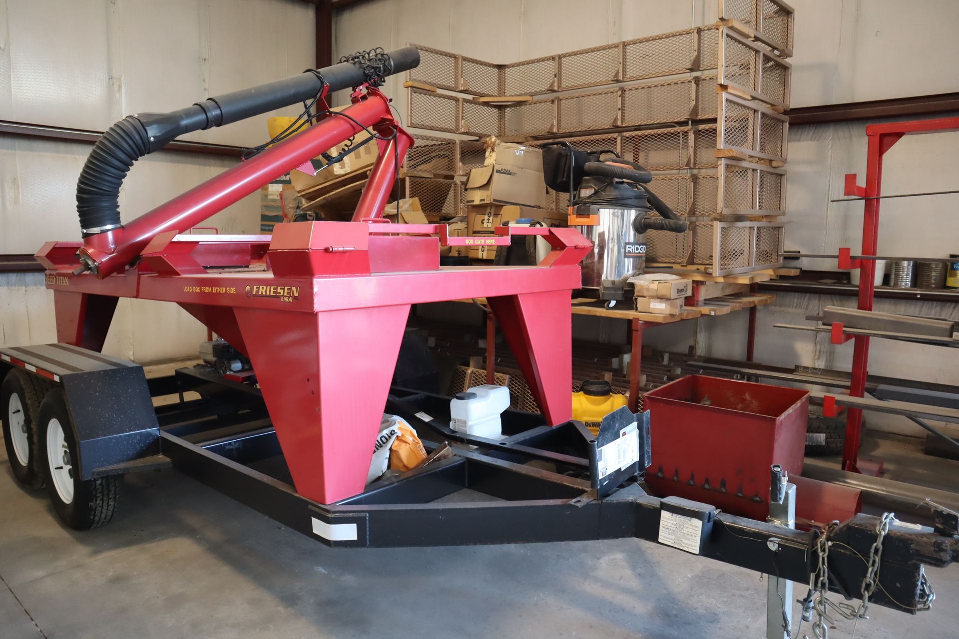 A red machine is on a trailer in a warehouse.