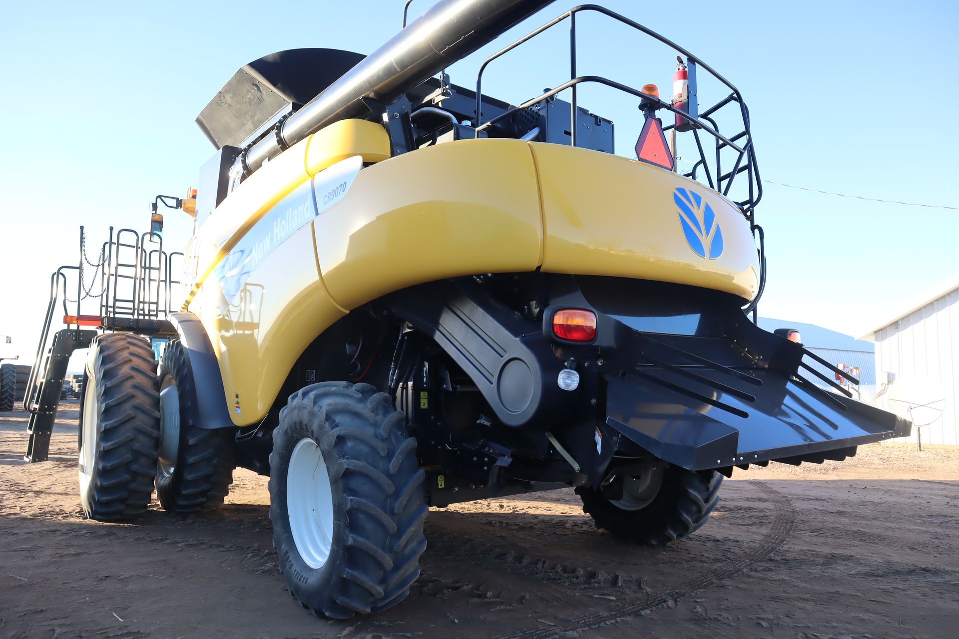 A new holland combine harvester is parked in the dirt