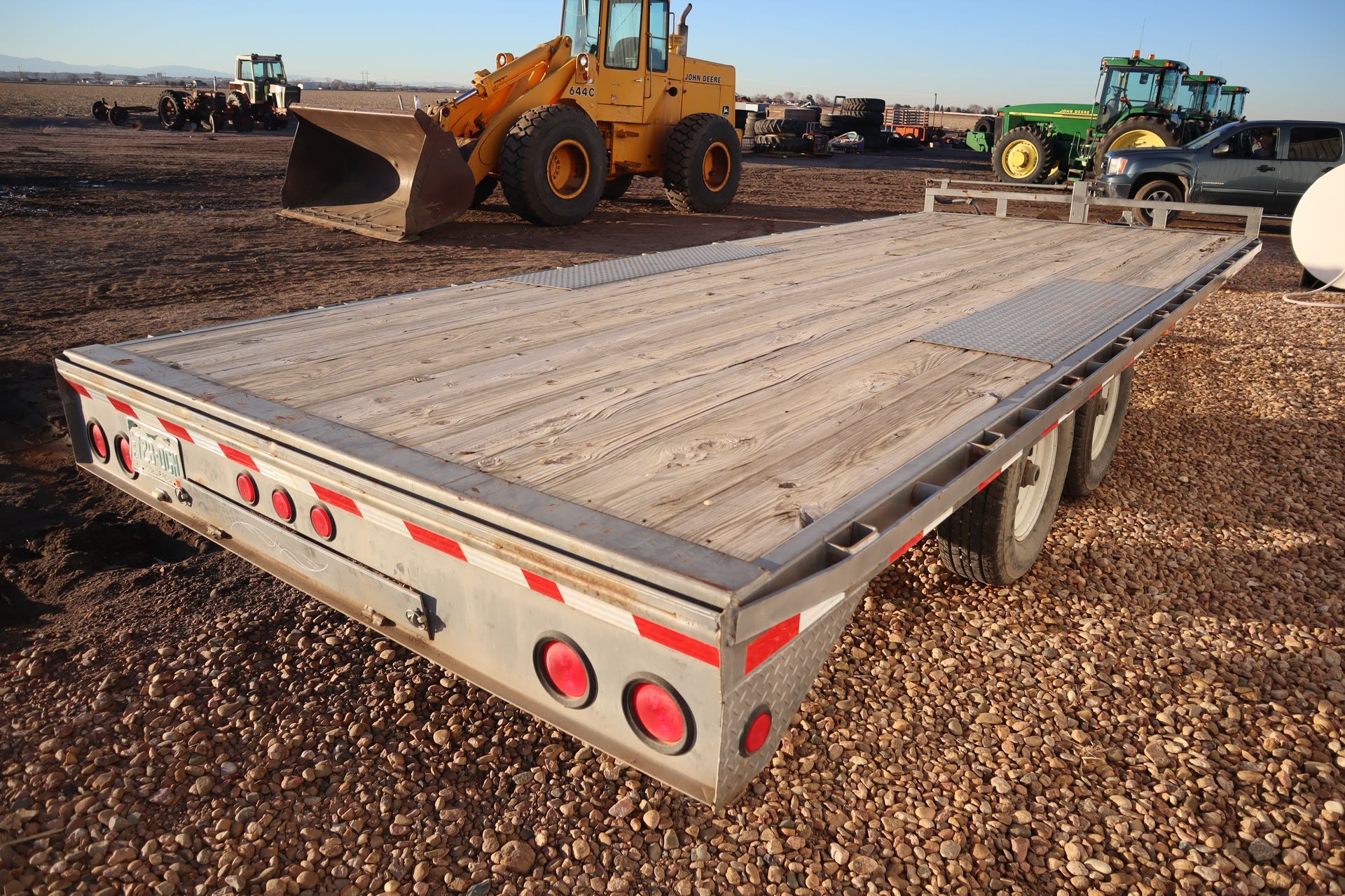 A flatbed trailer with a yellow tractor in the background