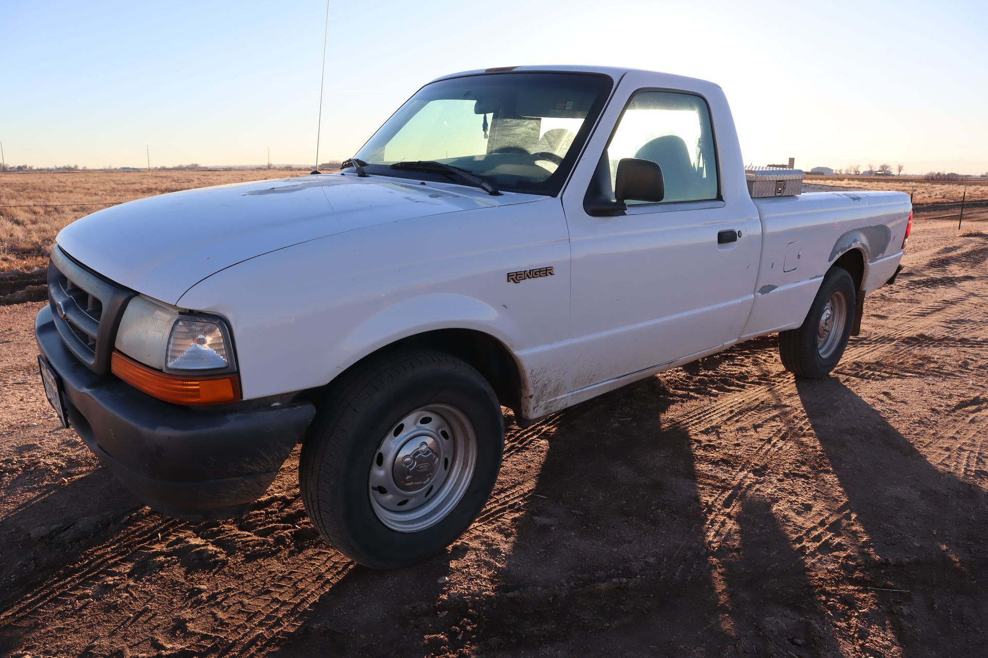 A white truck is parked in the middle of a dirt field