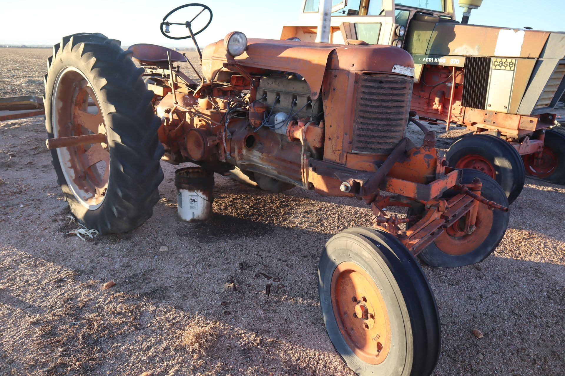 An old rusty tractor is parked in a dirt field