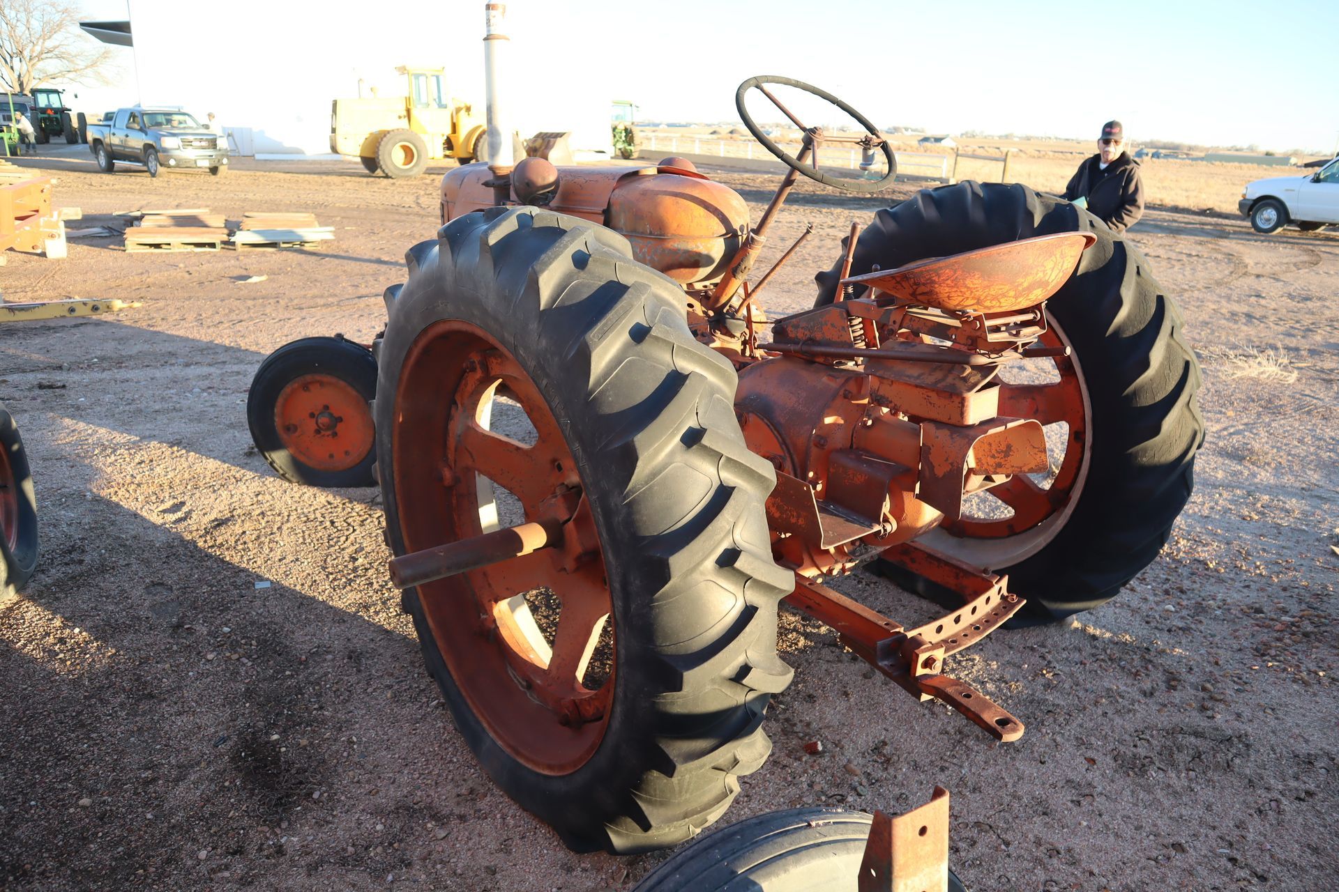 An old rusty tractor is parked in a dirt field