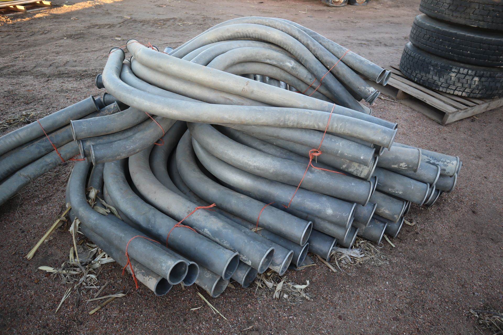 A pile of pipes are stacked on top of each other on the ground.
