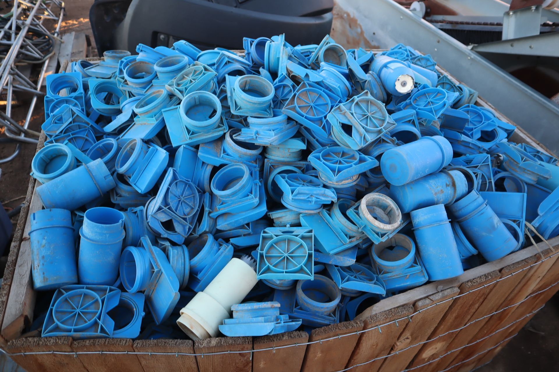 A wooden bin filled with blue plastic pipes and fittings.