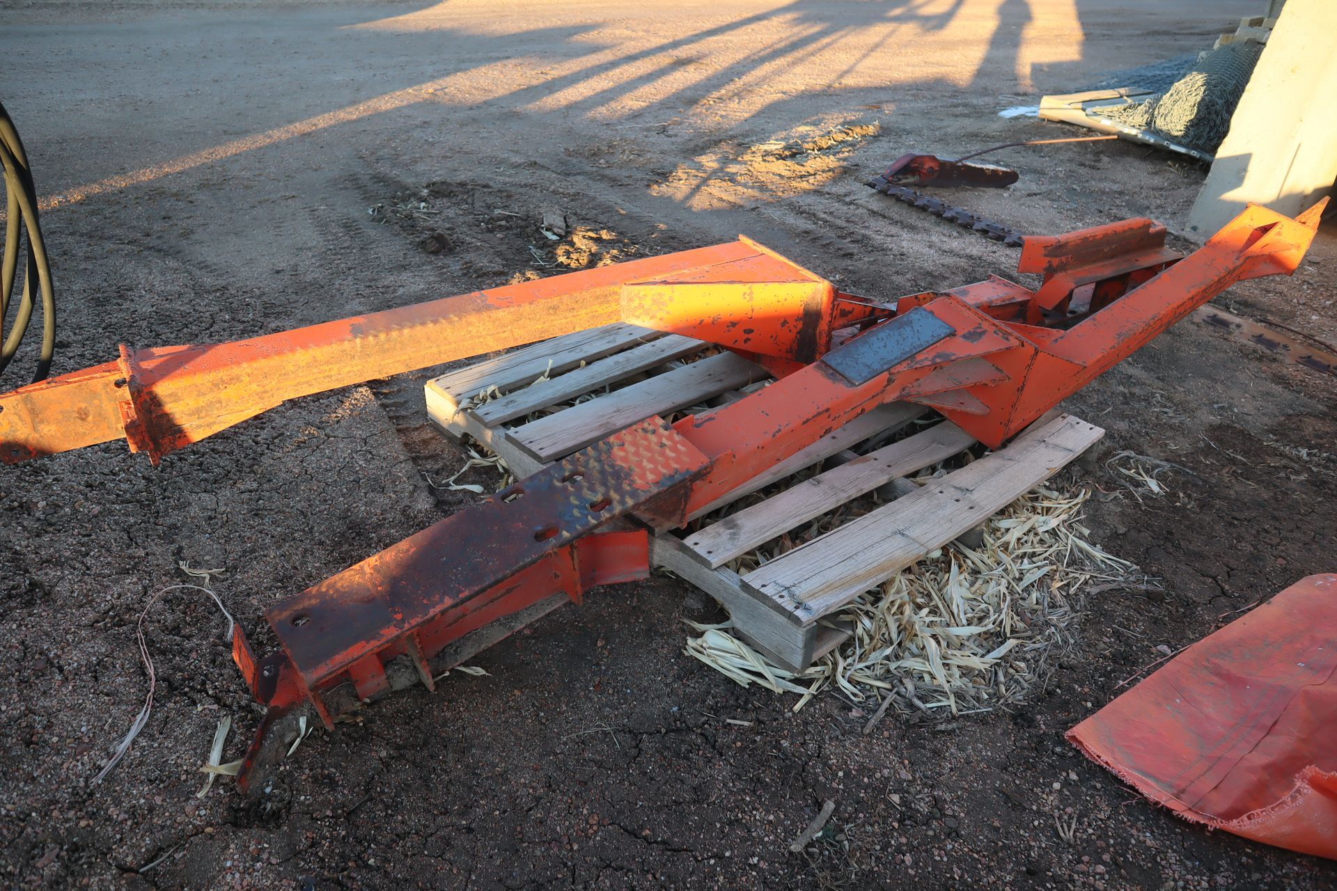 A piece of metal is laying on a wooden pallet on the ground.