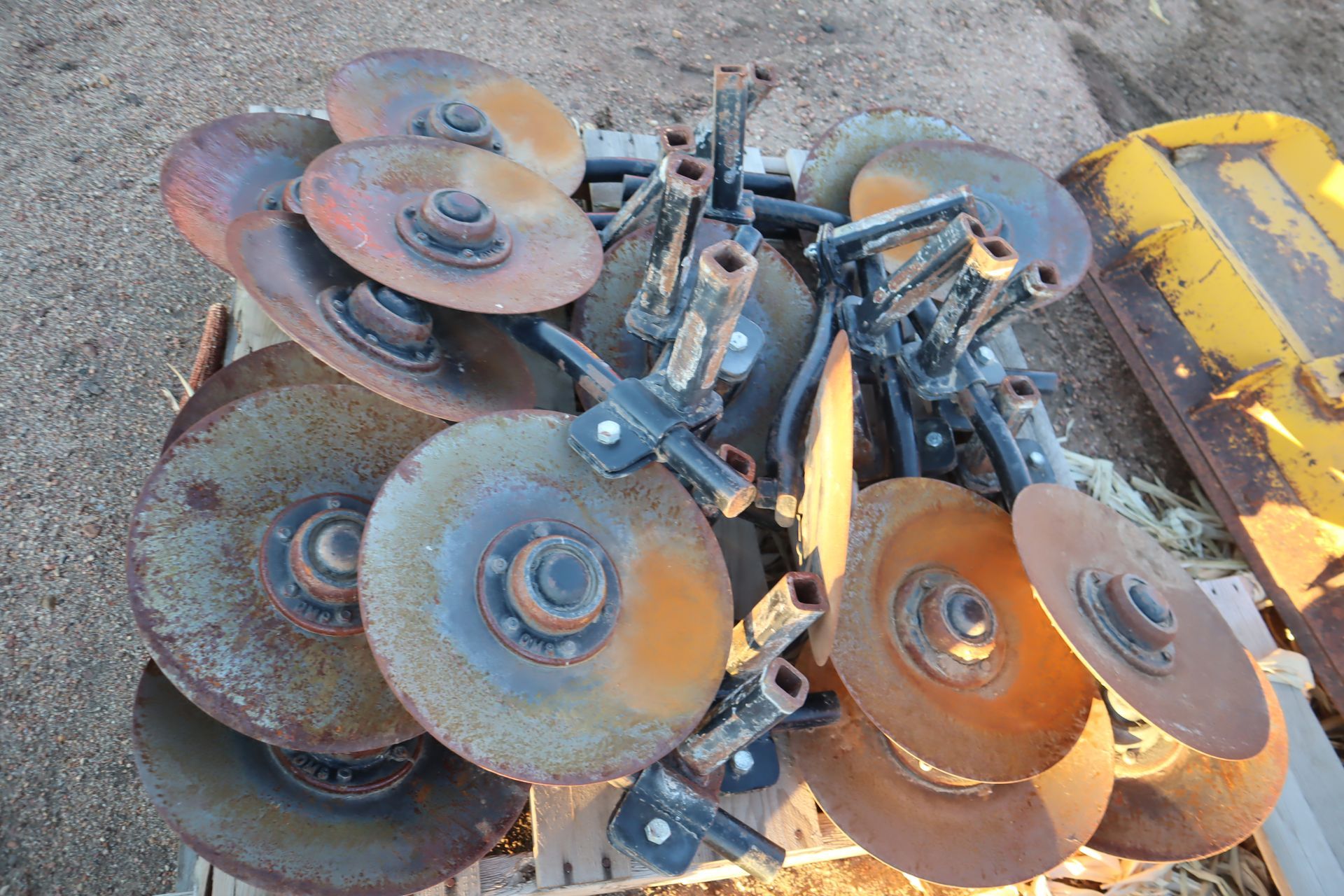 A bunch of rusty discs are stacked on top of each other on a wooden pallet.