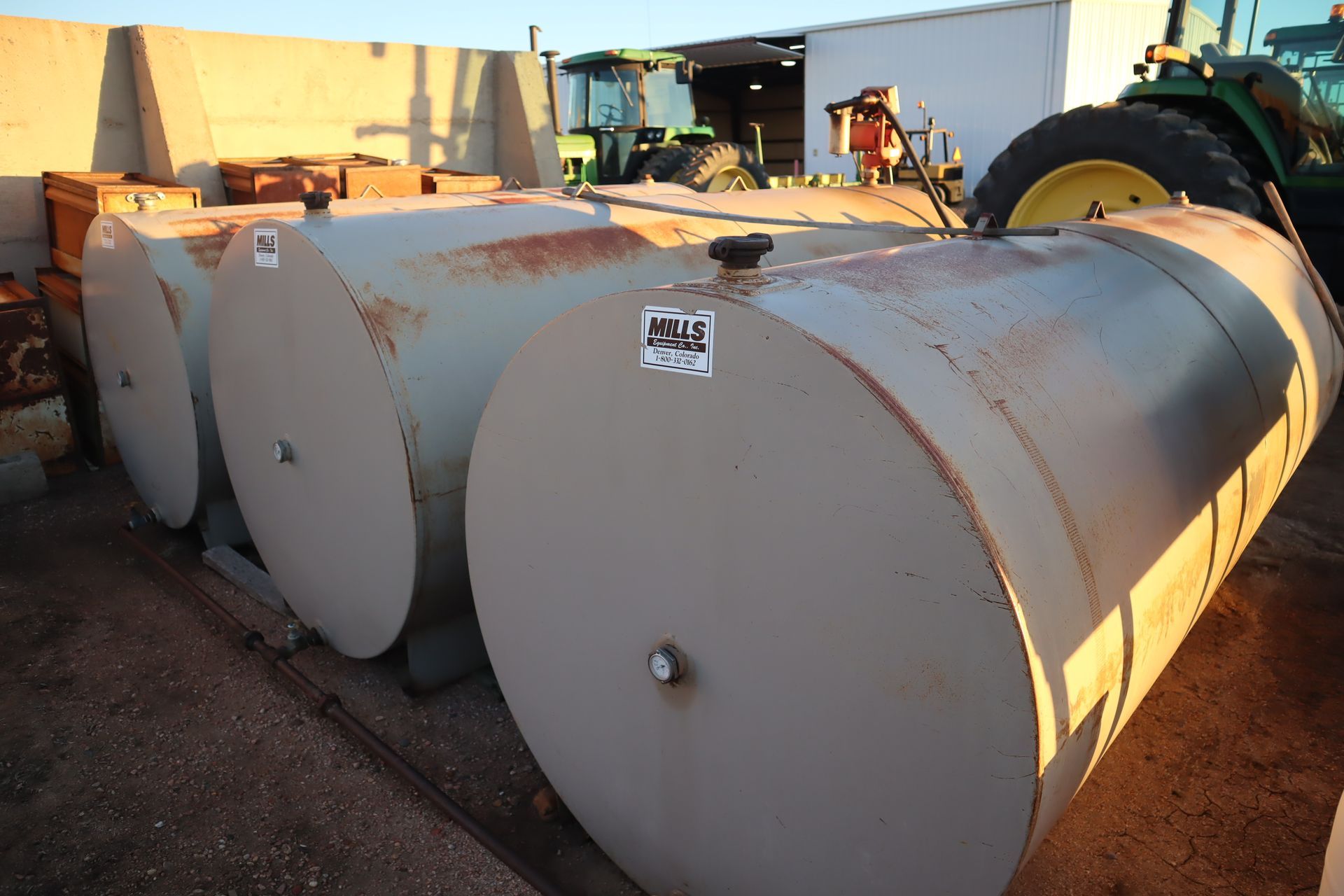 A tractor is parked behind a row of metal tanks