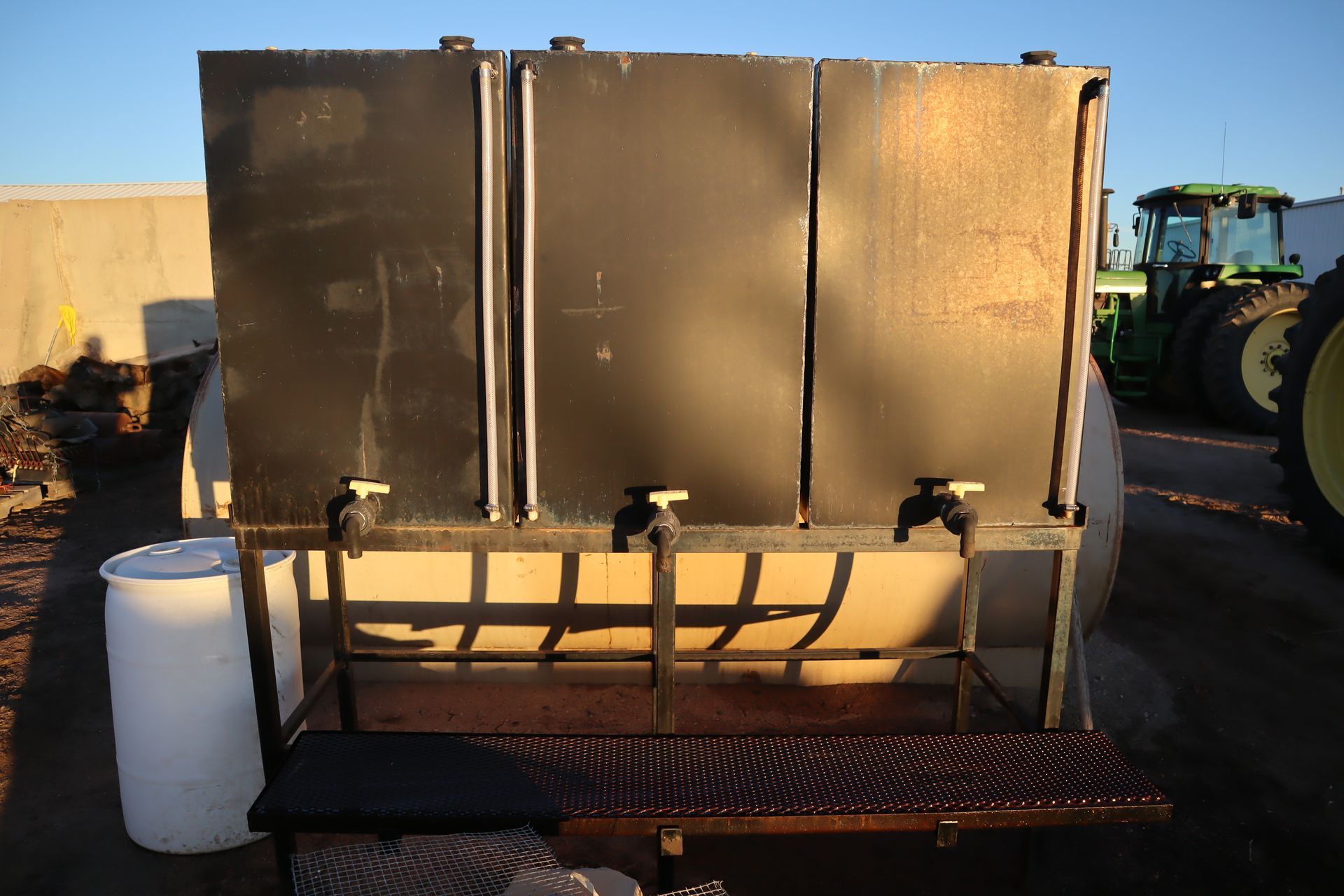 A tractor is parked next to a large metal tank