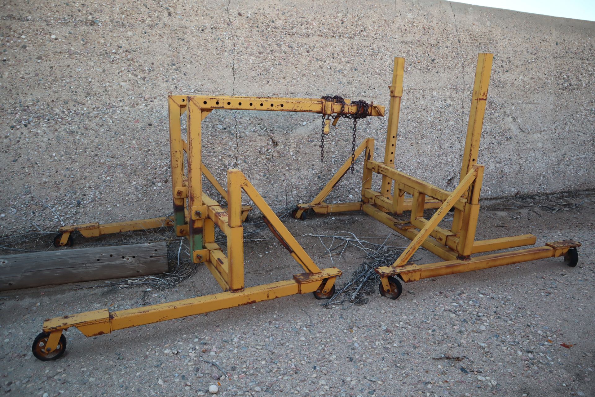 A yellow metal structure with wheels is sitting on a gravel road.
