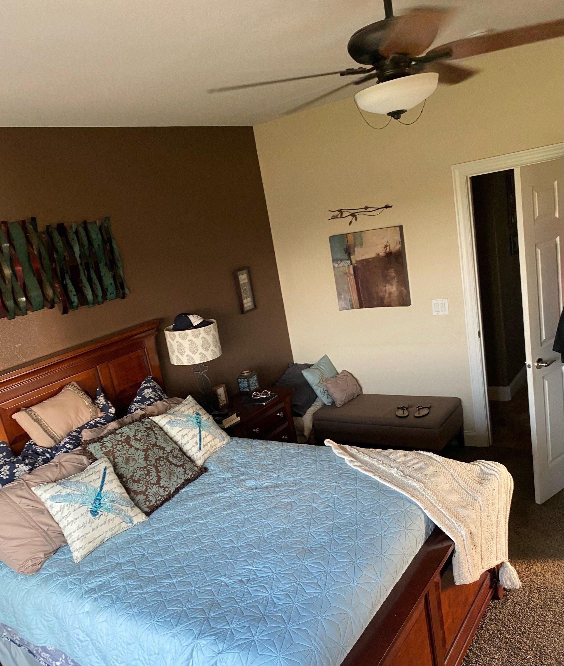 A bedroom with a bed and a ceiling fan