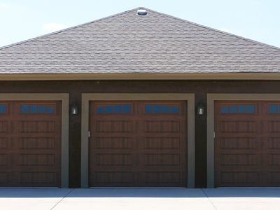 A house with three garage doors and a roof.
