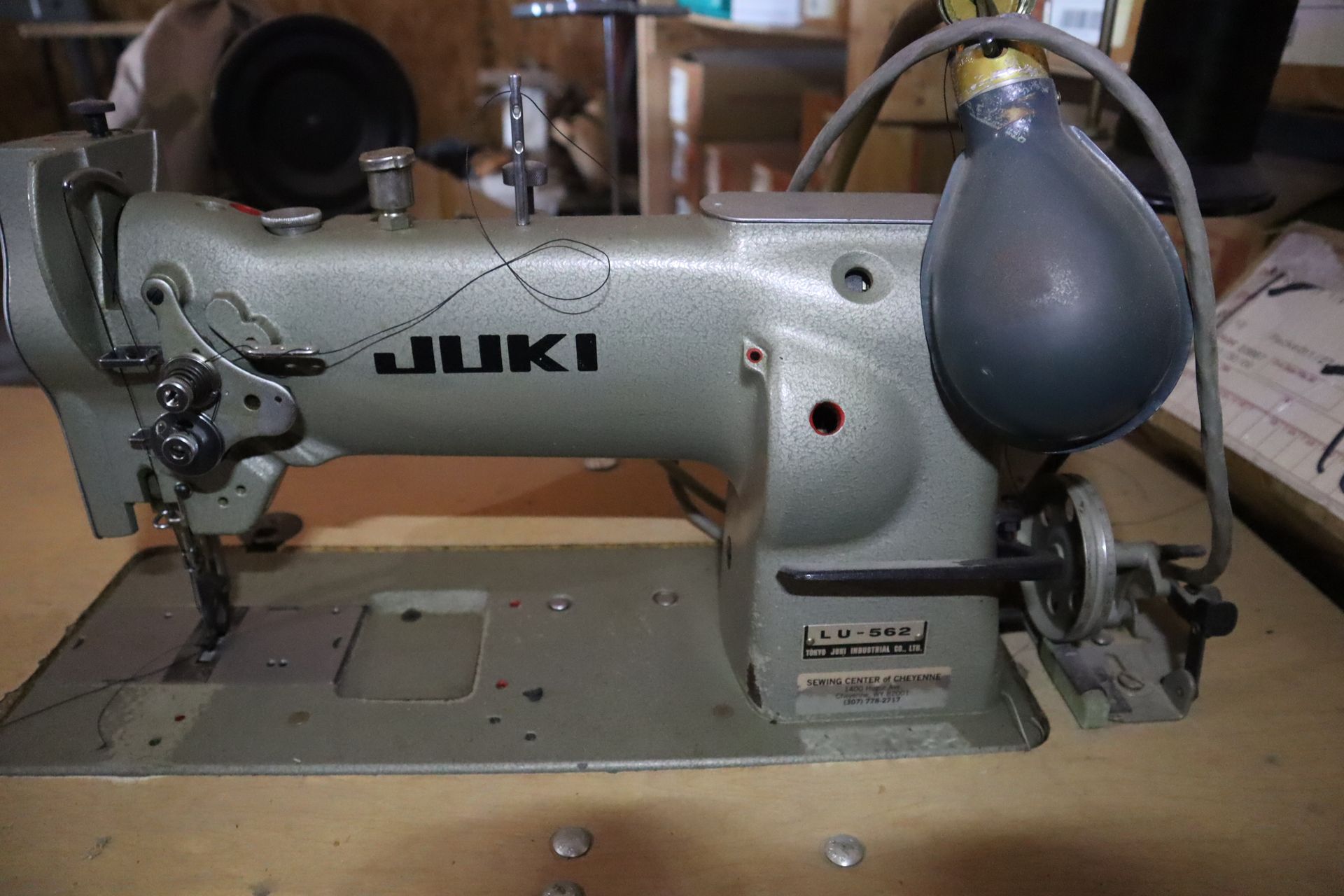 Juki industrial sewing machine, gray, on a wooden surface, with attached light and motor.