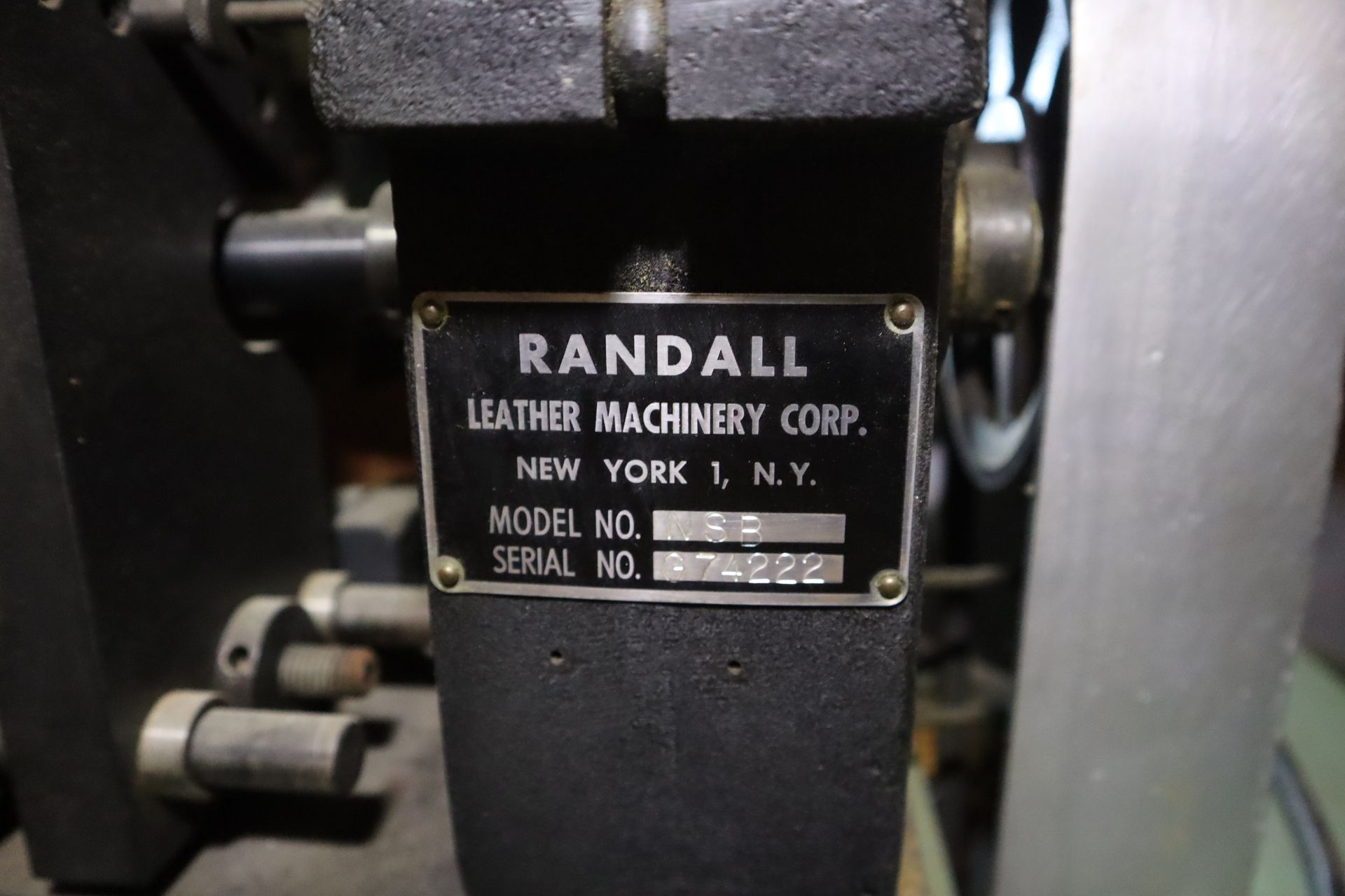 A nameplate from Randall Leather Machinery Corp, black and gold with model and serial numbers, in New York, I.Y.