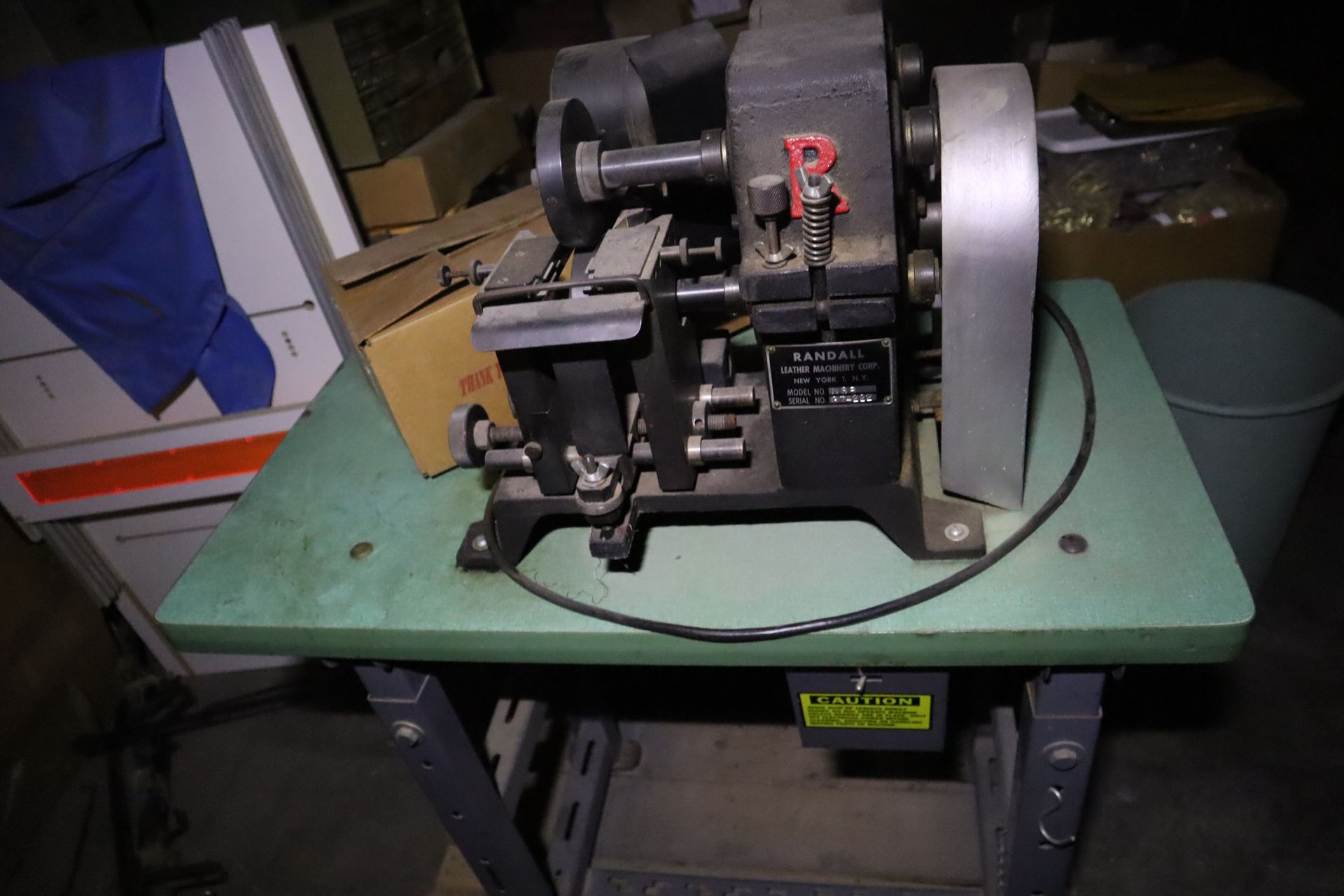 Black industrial machine on a green table, with a large silver wheel and an attached power cord.