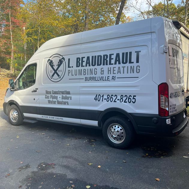 White L. Beaudreault Plumbing & Heating van parked on a tree-lined street in autumn